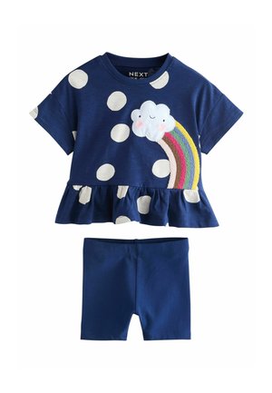 Tenue bleu marine pour tout-petit avec un haut à volants à pois blancs avec un nuage souriant et un arc-en-ciel brodé, assortie à un short uni.