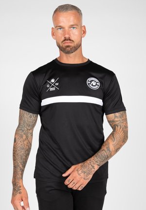 Black athletic shirt in a fitted design featuring a white horizontal stripe, logo on the left chest, and short sleeves. Smooth texture.
