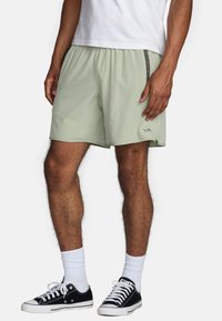 Shorts de bain vert clair en tissu léger. Dotés d'une taille élastique, de poches latérales et d'un logo sur l'ourlet inférieur.