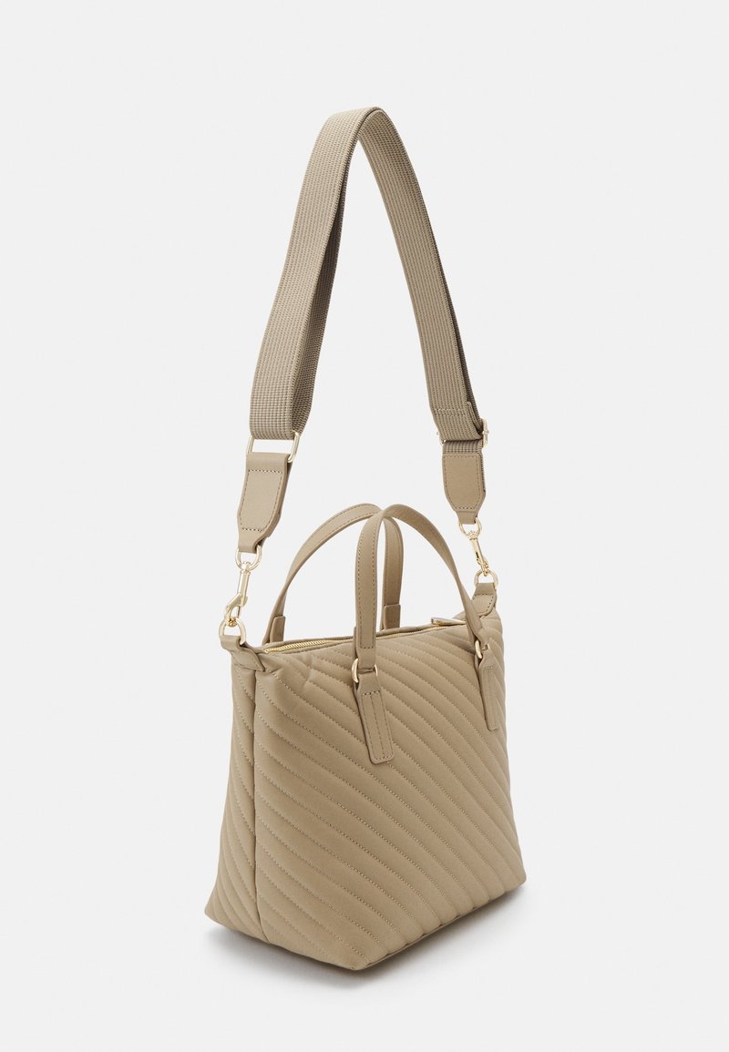 Bolso acolchado beige con dos asas superiores y una correa de tela ajustable. Herrajes en tono dorado y textura suave. Forma rectangular.