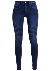 Los jeans de mezclilla azul oscuro presentan un diseño ajustado con patrones de costura acanalada en las rodillas, dos bolsillos delanteros y un cierre clásico de botón.
