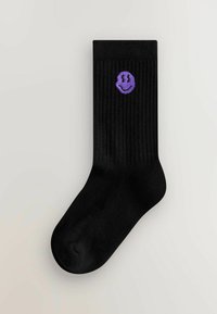 Sorte ribbede sokker med et lilla broderet smiley ansigt logo på oversiden. Glat tekstur med et klassisk design.