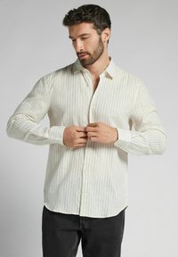 Lichtbeige overhemd met knopen en verticale strepen in verschillende kleuren, lange mouwen en een klassieke kraag. Zachte, gestructureerde stof.