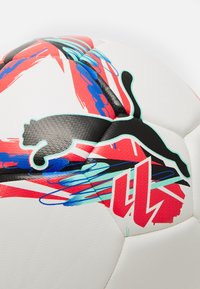 Valge jalgpall, millel on mustad, punased ja sinised graafikmustrid. Tekstuuriga pind ja ühe paneeli peal silmapaistev must Puma logo.