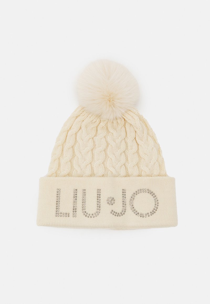 Cappello di maglia a trecce color crema con pompon soffice sulla parte superiore e risvolto che presenta un embellimento con logo di strass argentati.