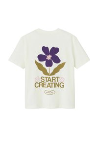 T-shirt en coton couleur crème clair avec un grand motif de fleur violette, des feuilles vertes et le texte "DÉMARREZ VOTRE CRÉATION" en marron et rose.