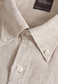 Camicia in lino beige chiaro con colletto a punta, con bottoni in plastica bianchi e un semplice motivo testurizzato. L'etichetta riporta "Oscar Jacobson, Regular."
