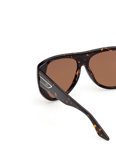 Gafas de sol con lentes marrón carey y patillas gruesas, que presentan una placa con el logo plateado de GCDS en la varilla.