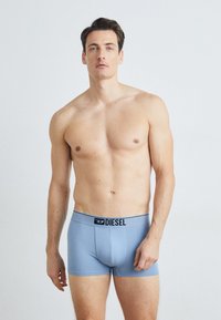 Blue boxer briefs made from soft fabric with a black branded waistband. The fit is snug, designed for comfort and support.