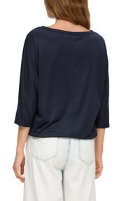 Marineblauwe, relaxed-fit top met een bootnek en 3/4 mouwen. Gemaakt van een zachte stof met een gladde textuur en minimale details.