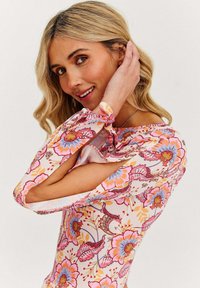 Květinová blůza s růžovými, oranžovými a modrými vzory, dlouhé rukávy s výřezy a lehkým materiálem.