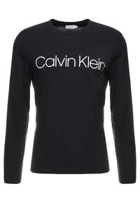 Schwarzes Langarm-T-Shirt aus Baumwolle, mit Rundhalsausschnitt und dem weißen "Calvin Klein"-Logo auf der Brust. Glatte Textur und taillierte Passform.