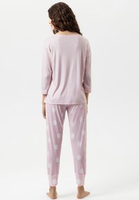 Ensemble de pyjama rose clair composé d'un haut à manches longues et d'un pantalon à pois avec une texture douce. Le pantalon est doté d'une ceinture élastique et de poignets.