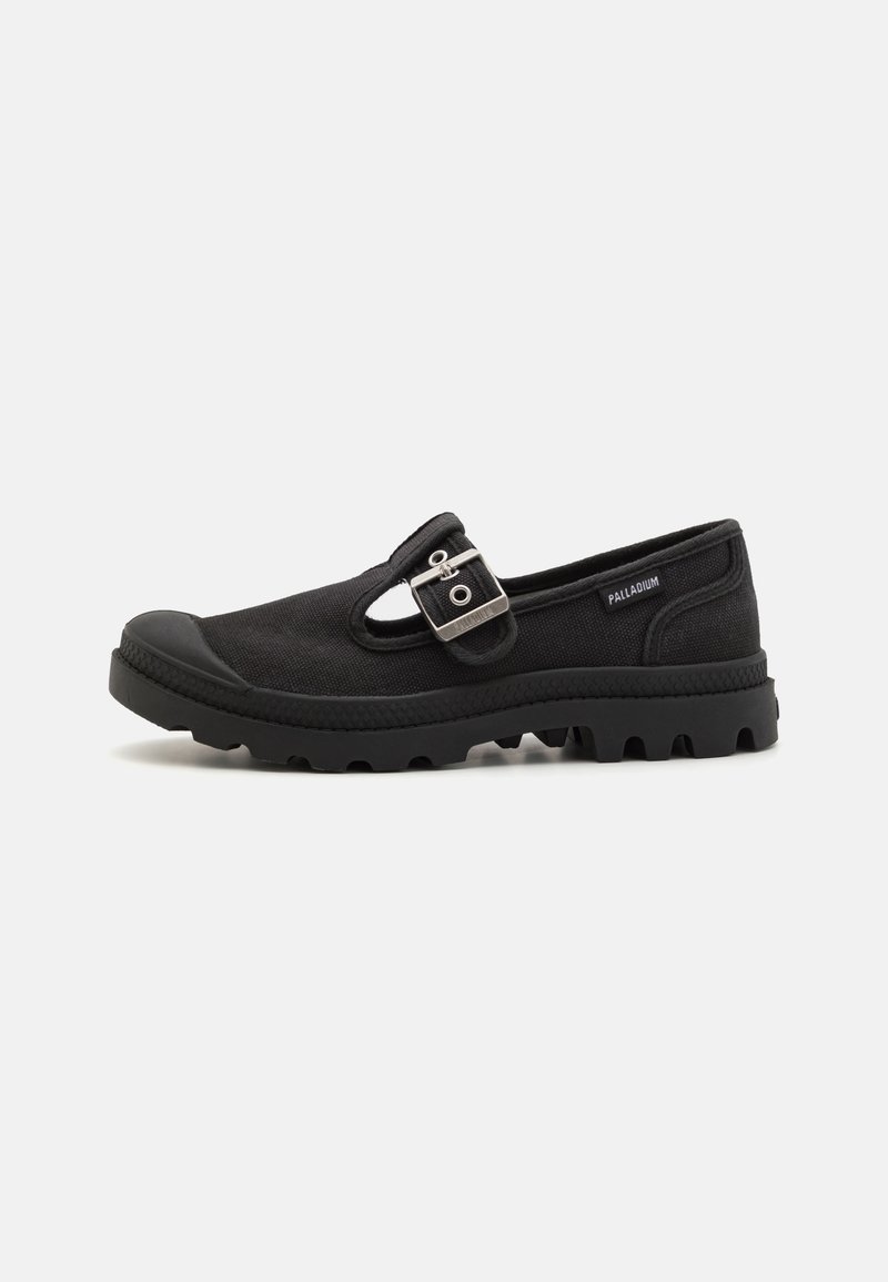 Zapatilla de lona negra con punta redonda, suela de goma con un patrón texturizado y una correa con un acento de hebilla de metal.