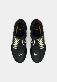 Par crnih Nike Total 90 nogometnih cipela s bijelim vezicama i logotipima, prikazanih odozgo na bijeloj pozadini.