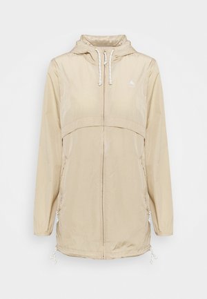 Beigen värinen kevyt hupullinen takki, jossa edessä vetoketju, säädettävät nyörit hupussa ja helmassa sekä kaksi sivutaskua vetoketjuilla.