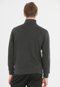 Mørkegrå pullover sweatshirt med høj krave og lange ærmer. Fremstillet af blødt stof, den har ribbede kanter og ærmer.