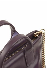 Borsa a tracolla in pelle viola con chiusura a zip e tracolla in catena dorata. Presenta due manici e una texture liscia, evidenziando un design minimalista.