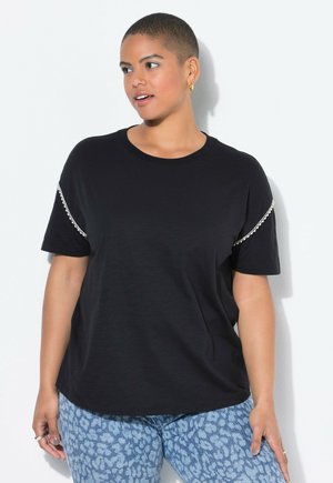 Camiseta negra de manga corta con un corte relajado, que presenta acentos decorativos de cadena en las mangas y una textura suave y lisa.