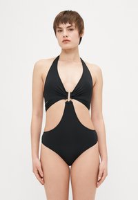 Svart heldrakt med halterneck, utskårne sider og gullakenter i midten. Glatt tekstur, minimalistisk design.