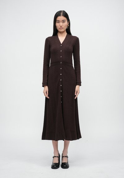 Long, chocolate-brown knitted dress with a V-neck, button-down front, and long sleeves. Features a textured pattern and a flared hem.