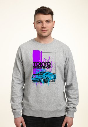 Grijze sweatshirt met een voorzijde graphic van een blauwe sportauto en paarse verfsplashes. Tekst luidt "Tokyo Speed Shop." Eenvoudig, casual ontwerp.