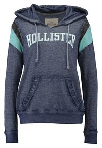 Mörkblå hoodie med dragsko i huvan, ficka fram och "HOLLISTER"-logotyp. Har aquafärgad och kolgrå accent på ärmarna. Mjuk tygstruktur.