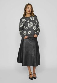 Grau gestrickter Pullover mit weißem Blumenmuster, kombiniert mit einem schwarzen Leder-Maxiskirt. Der Rock hat eine glatte Textur und eine ausgestellte Silhouette.