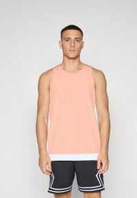 Rosa treningstopp med mesh-struktur og hvite sidepaneler, kombinert med svarte mesh-shorts med hvite striper.