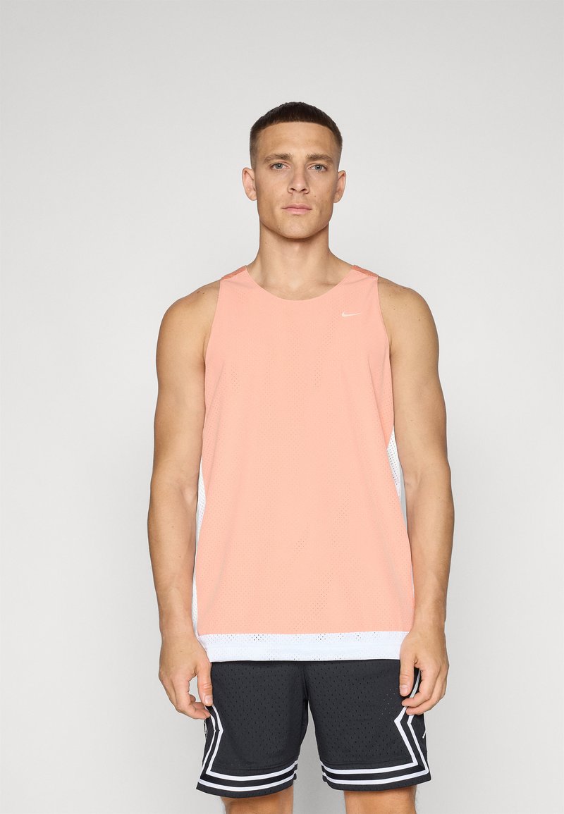 Rosa treningstopp med mesh-struktur og hvite sidepaneler, kombinert med svarte mesh-shorts med hvite striper.
