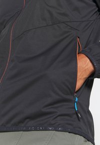 Schwarze leichte Jacke mit orangefarbenen Akzenten, Reißverschlusstaschen, weicher Textur und elastischen Bündchen. Verfügt über einen Kordelzug am Saum und atmungsaktiven Stoff.