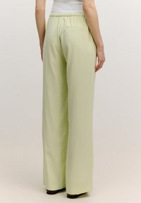 Lichtgroene, wijde broek met een elastische tailleband, een soepele textuur en een enkele achterzak. Ontworpen voor een ontspannen pasvorm.