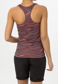 Meko kuvioitu urheilullinen toppi viininpunaisena, jossa on racerback-muotoilu. Yhdistetty mustiin shortseihin, joissa on verkkomateriaalista yksityiskohtaa helmassa.