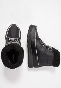 Black waterproof winter boots with a fluffy black lining, silver accents, textured rubber soles, and rounded toe design.