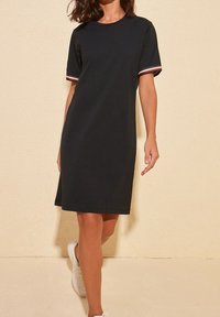 Černé tričko-šaty s krátkými rukávy, zdobené červenobílými pruhovanými detaily. Jednoduchý design, délka ke kolenům, vyrobené z měkké látky.