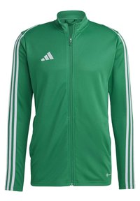 Groene ritsjack van gladde stof, met witte drie-streeps accenten langs de mouwen en een logo op de borst.