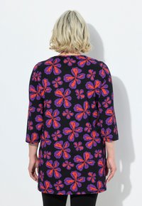 Tunic nera con vivaci motivi di farfalle rosse e viola. Ha maniche a tre quarti e un design ampio e fluido.