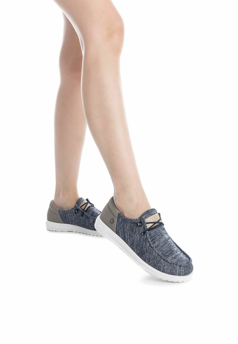Zapatos slip-on de punto azul con acentos grises, cordones elásticos y suelas de goma blanca. Presentan un acabado texturizado y un diseño de punta redonda.