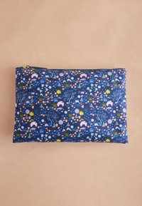 Rektangulär zip-försedd påse i marinblått med färgglada mönster av blommor, träd, berg, hus och sol på beige bakgrund.
