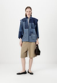 Τζάκετ από τζην με σχέδιο από μπαλώματα, δύο τσέπες με μπαλώματα, μανίκια κιμονό; συνδυασμένο με μπεζ σορτς και μαύρες εσπαντρίγιες. Σκοτεινή τσάντα χειρός.