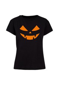 Musta t-paita, jossa on oranssi Halloween-kurpitsan kasvot -grafiikka, jossa on terävät hampaat ja kärjistetyt silmät. Lyhyet hihat ja rento istuvuus.