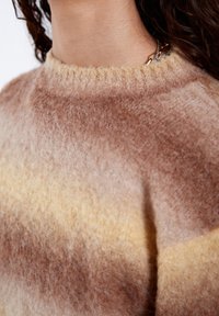 Strickpullover mit weicher, flauschiger Textur und einem Farbverlauf in Braun- und Cremetönen; runder Halsausschnitt und minimalistische Designdetails.