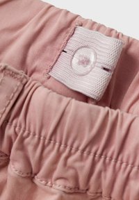 Nahaufnahme eines pinken elastischen Taillenbands mit verstellbarem Knopf und Stoffknopfloch zur Anpassung der Größe.