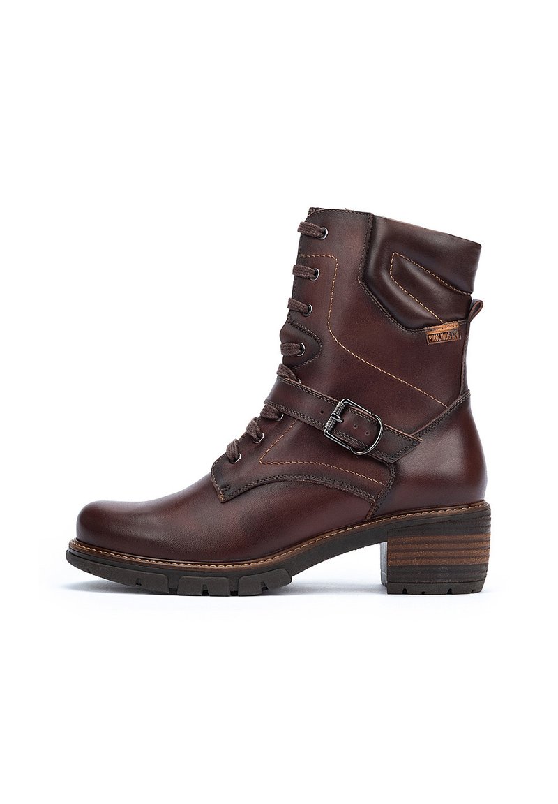 Brown leather ankle boot featuring a lace-up design, side buckle, stacked heel, and contrasting stitching. Textured surface and sturdy sole.