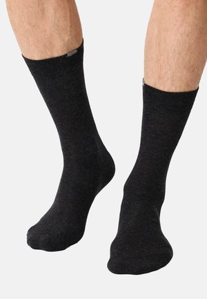 Schwarze Sportsocken aus weichem Stoff mit einem gerippten Bund, die eine glatte Textur und ein schlichtes Design aufweisen. Keine sichtbaren Muster oder Akzente.