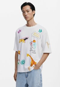 Witte t-shirt met korte mouwen, voorzien van kleurrijke dieren- en abstracte patronen, met een relaxed fit en ronde hals.