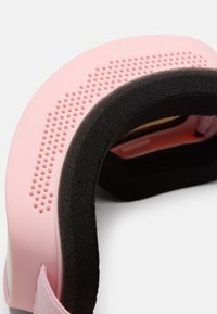 Primer plano de un visor de realidad virtual rosa con acolchado negro de espuma y huecos de ventilación en el borde exterior del marco.