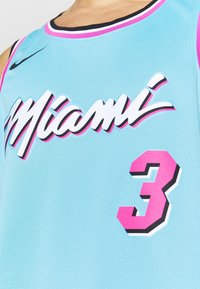 La camiseta de baloncesto azul claro presenta "Miami" en una fuente blanca en negrita y acentos en rosa intenso. El número "3" se muestra en rosa intenso con un borde negro.