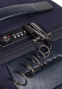 Valigia blu navy realizzata in materiali tessili e in pelle, con lucchetto combinazione, doppi cursori della cerniera e attacco a cavo avvolto.