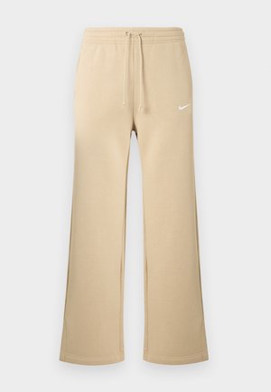 Pantalon de survêtement beige avec une taille à cordon, un design à jambes larges et un petit logo blanc Nike sur la cuisse gauche. Tissu lisse en mélange de coton.